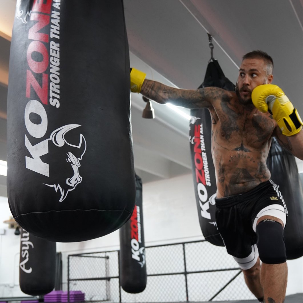 KO Zone Miami fighter delivering knee strike on KO Zone branded heavy bag